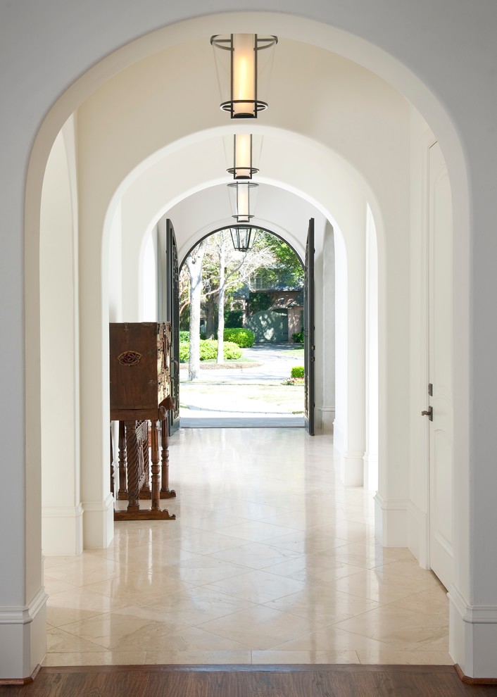 Design ideas for a mediterranean hallway in Dallas with white walls and beige floors.