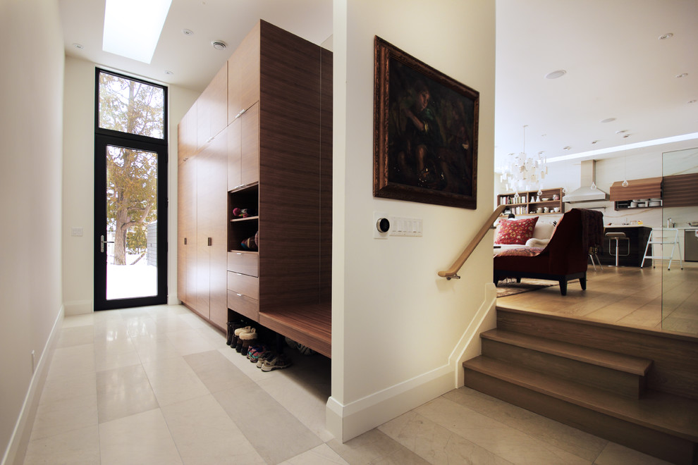 Exemple d'une entrée moderne de taille moyenne avec un vestiaire, un mur blanc, parquet clair et une porte en verre.