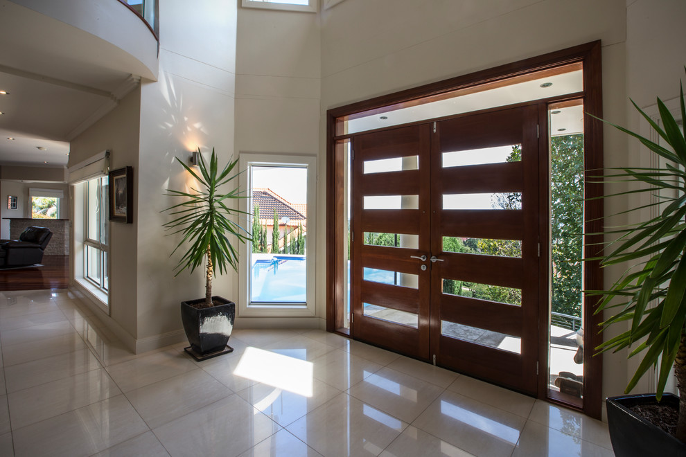 Foto di un ingresso minimal di medie dimensioni con pavimento in gres porcellanato, una porta a due ante, una porta in legno bruno e pavimento beige