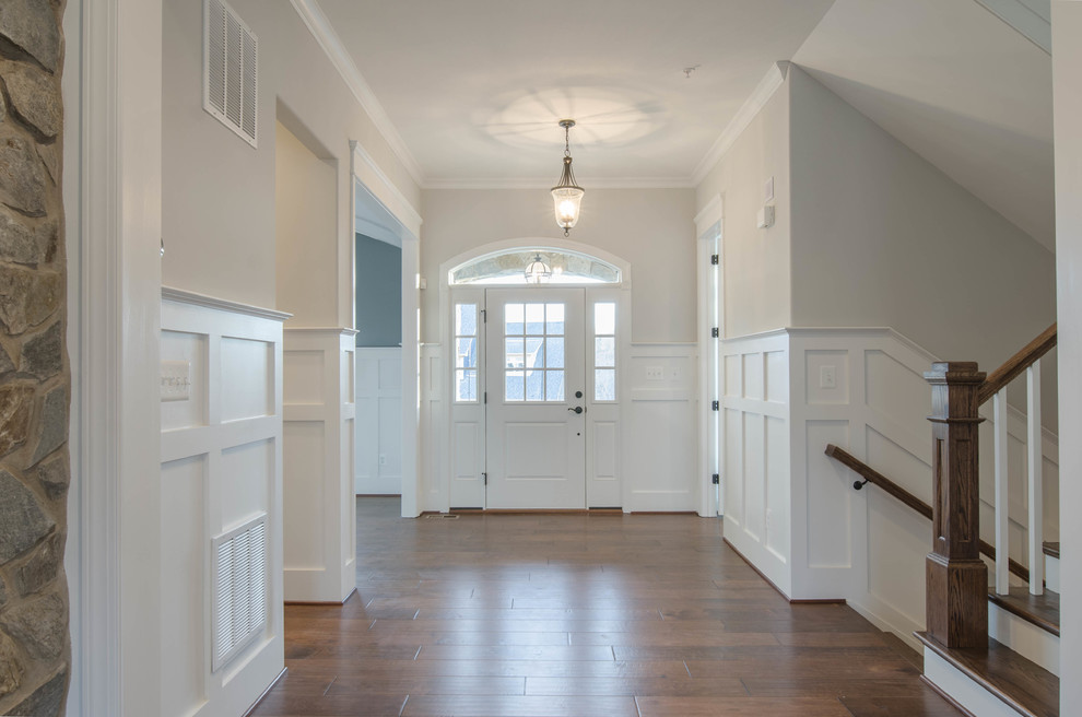 Idées déco pour un hall d'entrée classique de taille moyenne avec un mur blanc, parquet foncé, une porte simple, une porte blanche et un sol marron.