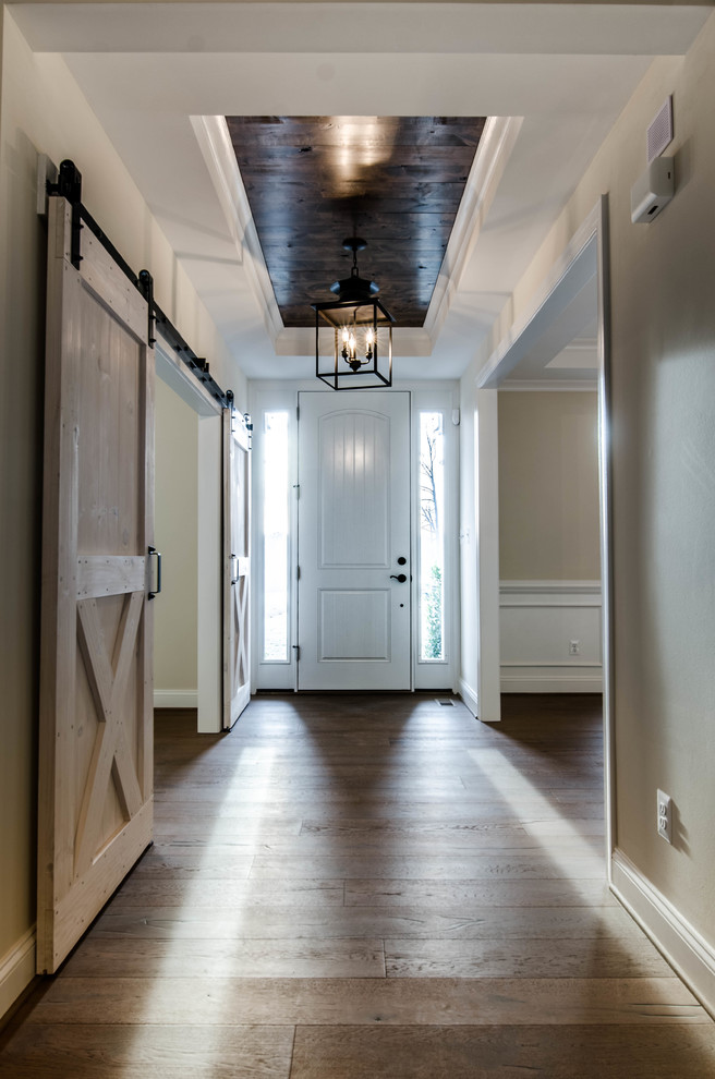 Ejemplo de entrada clásica renovada de tamaño medio con paredes beige, suelo de madera oscura, puerta blanca y suelo marrón