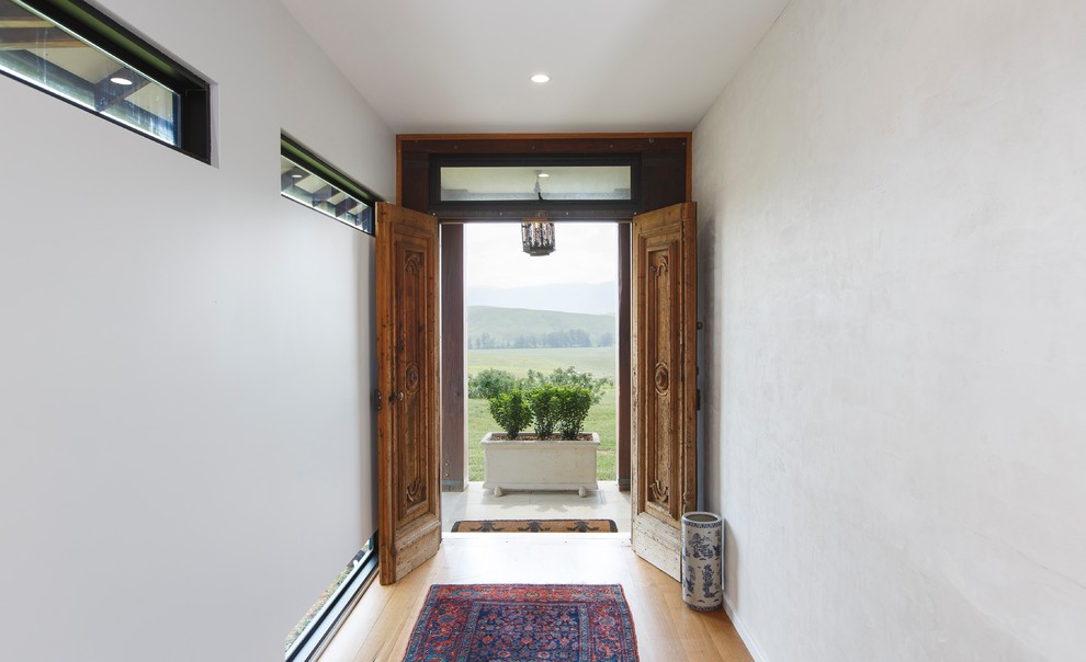 Immagine di un ingresso mediterraneo di medie dimensioni con pavimento in legno massello medio, una porta a due ante, una porta in legno bruno e pavimento marrone