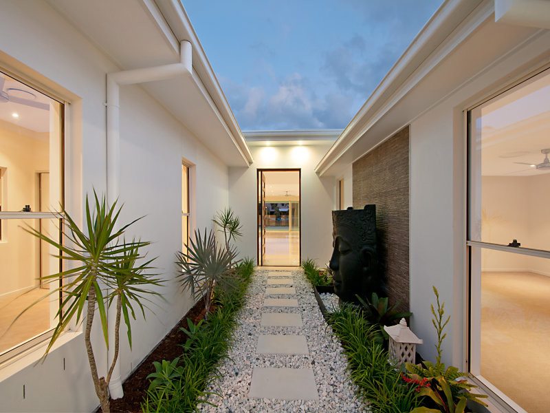 Immagine di una porta d'ingresso etnica di medie dimensioni con pareti bianche, pavimento in marmo, una porta a pivot e una porta in legno bruno