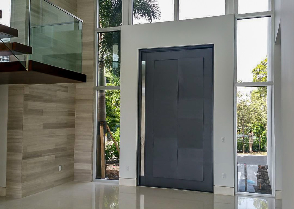 Idee per una grande porta d'ingresso minimalista con pareti beige, pavimento in pietra calcarea, una porta a pivot e una porta grigia