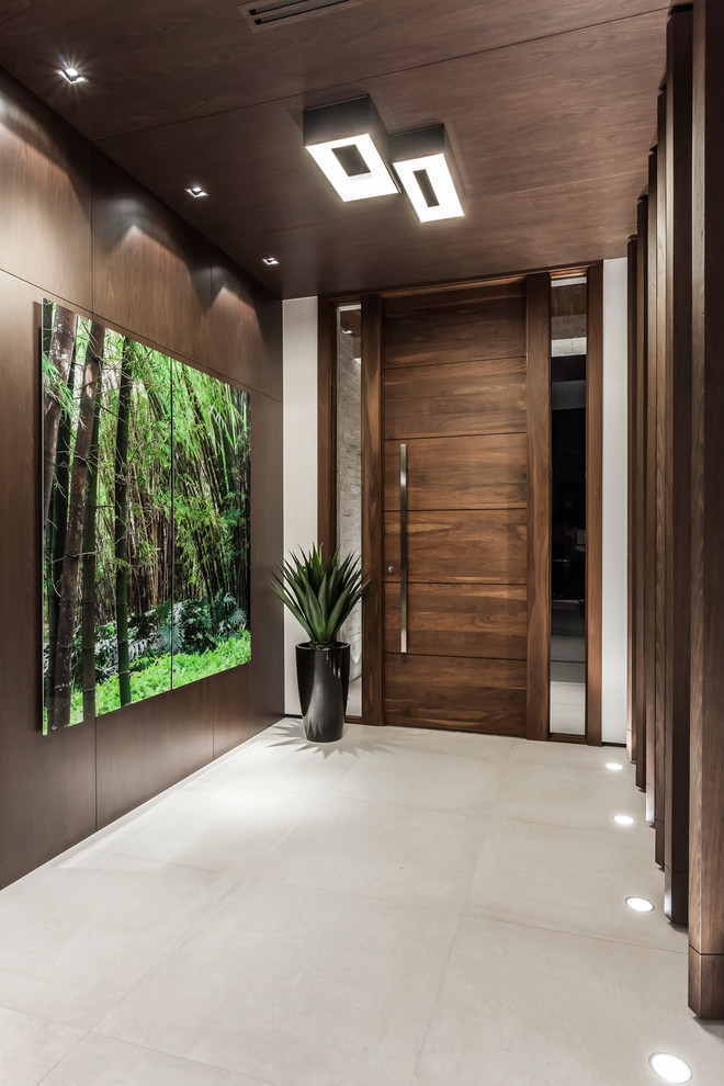 マイアミにあるラグジュアリーな広いコンテンポラリースタイルのおしゃれな玄関ロビー (茶色い壁、磁器タイルの床、濃色木目調のドア、グレーの床) の写真