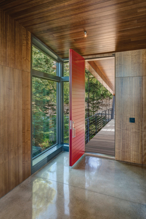Großer Moderner Eingang mit Korridor, brauner Wandfarbe, Betonboden, Einzeltür und roter Haustür in Sonstige