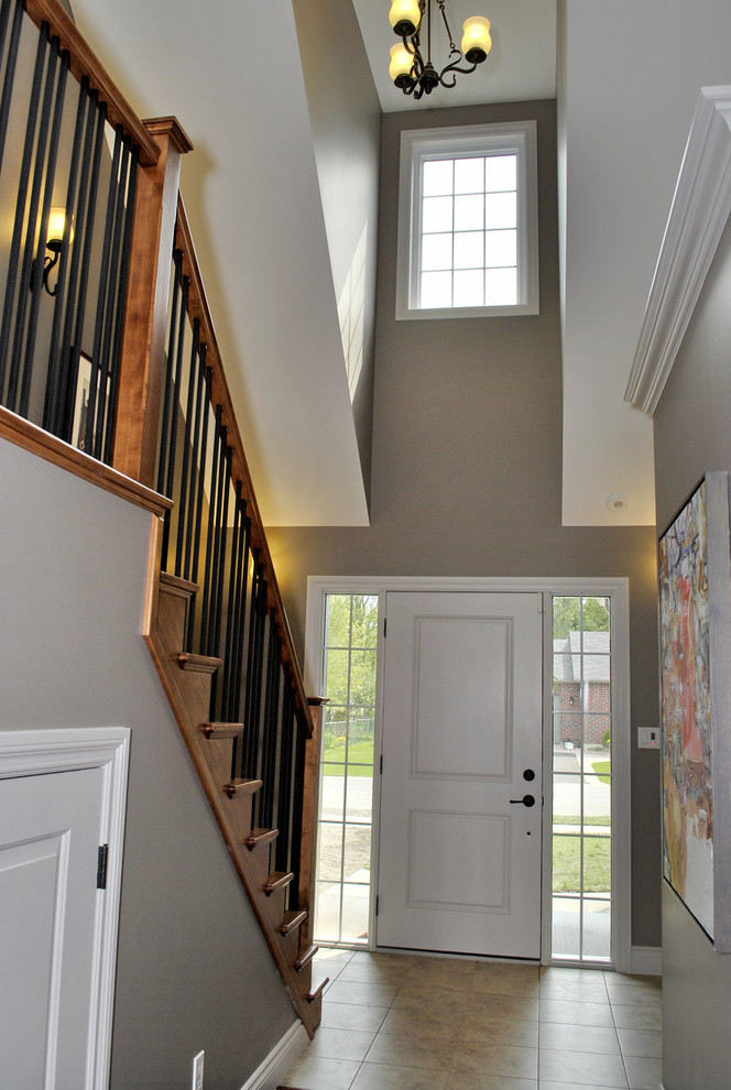 Foto di un corridoio american style di medie dimensioni con pareti beige, pavimento con piastrelle in ceramica e una porta bianca