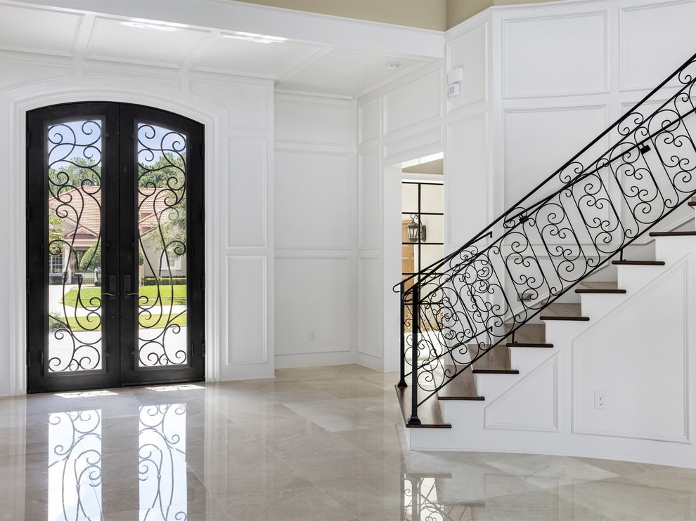Пример оригинального дизайна: огромная входная дверь в стиле неоклассика (современная классика) с белыми стенами, мраморным полом, двустворчатой входной дверью и стеклянной входной дверью