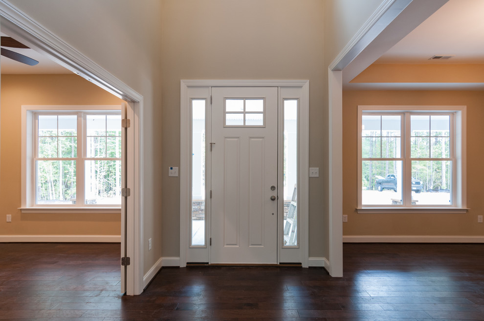 Exempel på en liten amerikansk ingång och ytterdörr, med vita väggar, mörkt trägolv, en enkeldörr, en vit dörr och brunt golv
