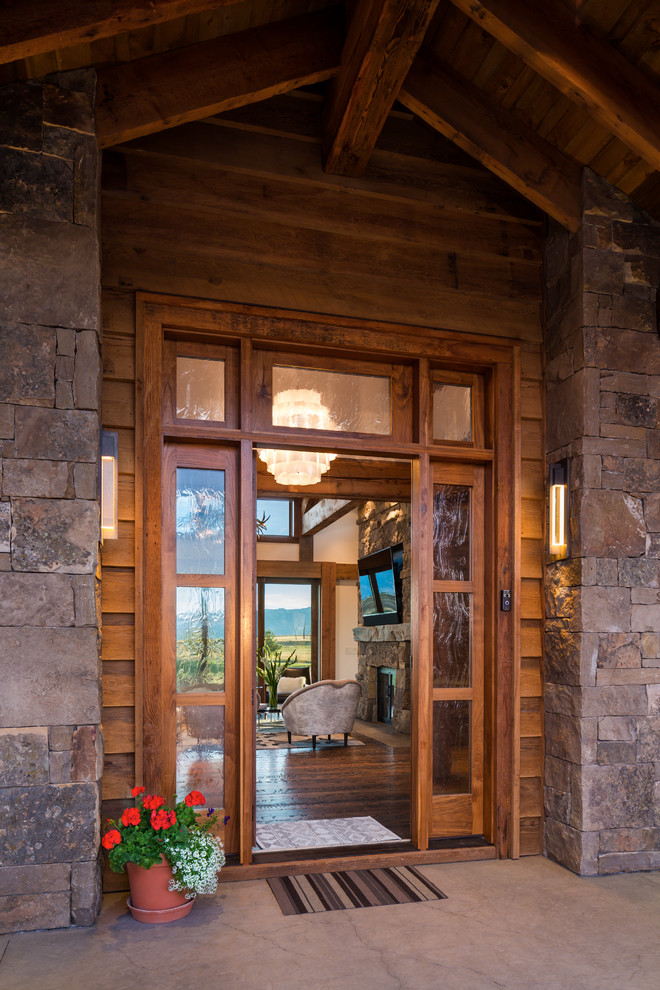 Réalisation d'une grande porte d'entrée chalet avec un sol en bois brun, une porte simple, une porte en bois foncé et un sol marron.