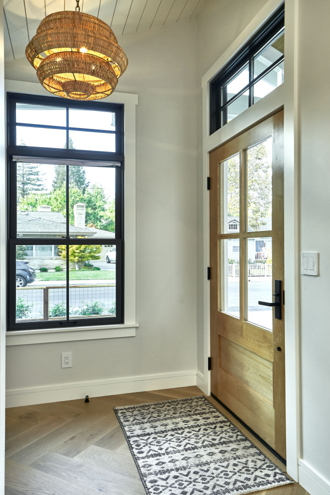Пример оригинального дизайна: маленькое фойе в стиле неоклассика (современная классика) с серыми стенами, светлым паркетным полом, одностворчатой входной дверью, коричневой входной дверью, серым полом и сводчатым потолком для на участке и в саду