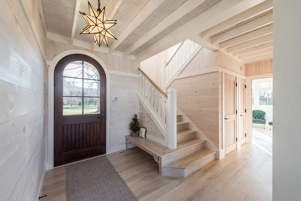 Idée de décoration pour une porte d'entrée chalet de taille moyenne avec un mur beige, parquet clair, une porte simple, une porte en bois foncé et un sol beige.