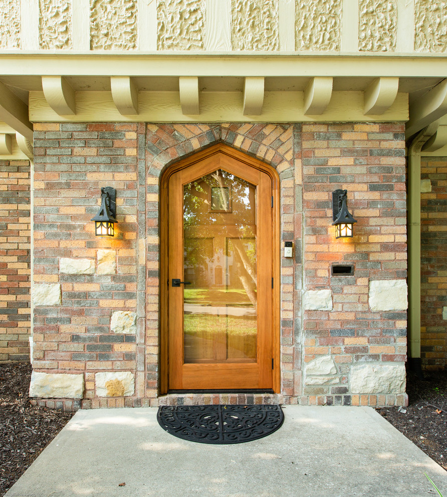 Entryway - mid-sized craftsman concrete floor and gray floor entryway idea in Kansas City with a medium wood front door and brown walls