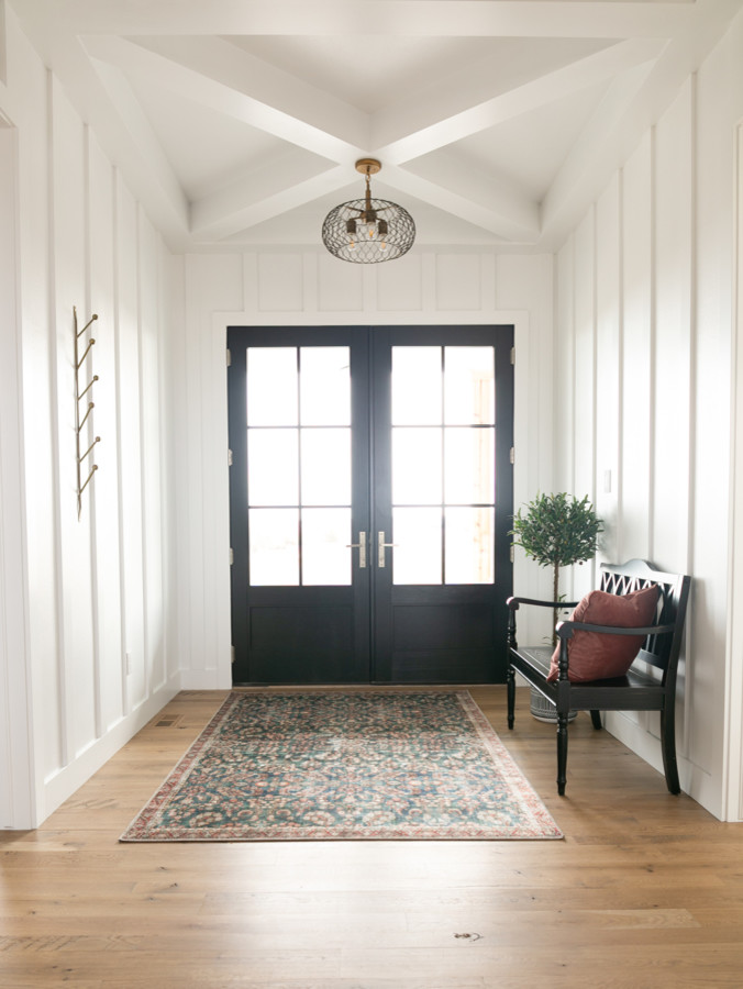 デンバーにある高級な中くらいなカントリー風のおしゃれな玄関ロビー (白い壁、無垢フローリング、黒いドア、茶色い床) の写真
