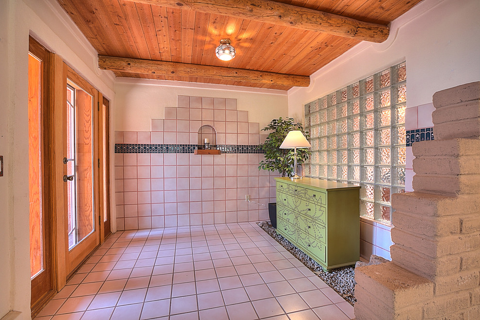 アルバカーキにある高級な広いサンタフェスタイルのおしゃれな玄関ロビー (白い壁、磁器タイルの床、ガラスドア) の写真