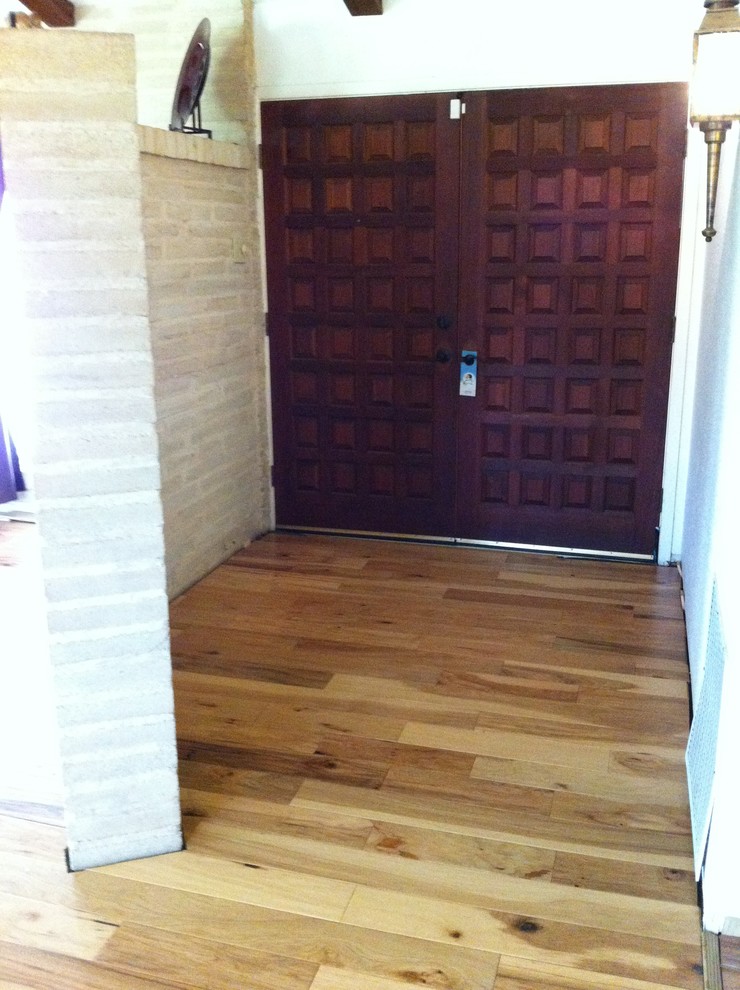 Modelo de distribuidor rústico grande con paredes beige, suelo de madera clara, puerta doble y puerta de madera oscura