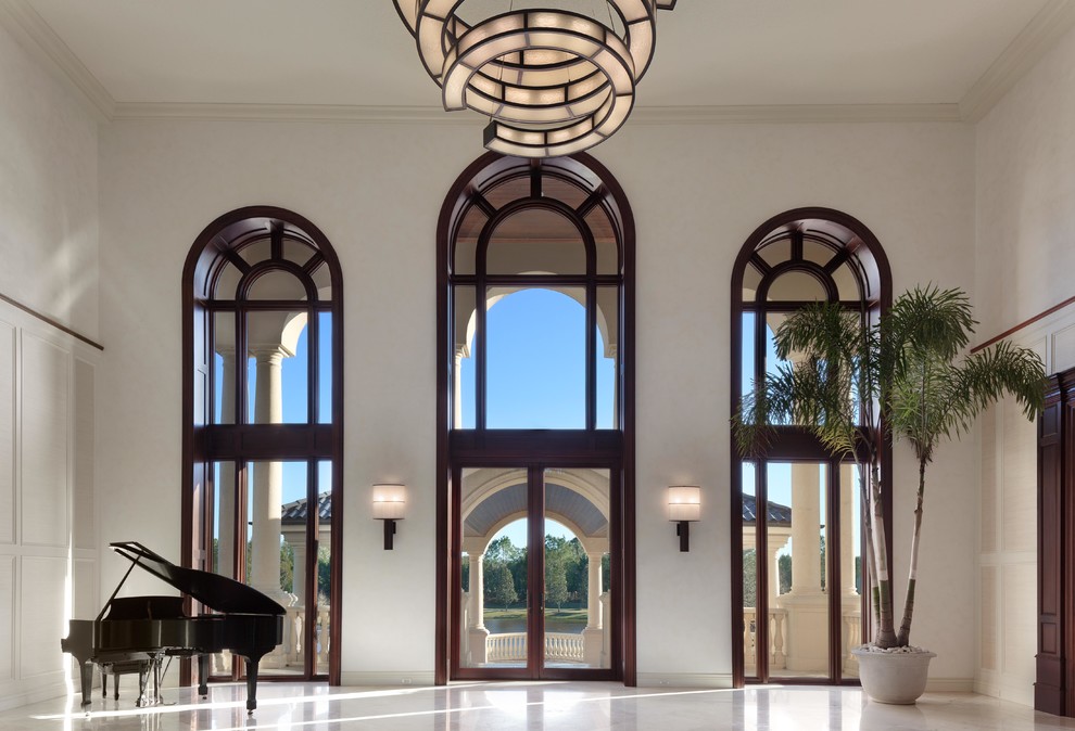 Пример оригинального дизайна: огромное фойе в стиле неоклассика (современная классика) с белыми стенами, мраморным полом, двустворчатой входной дверью и стеклянной входной дверью