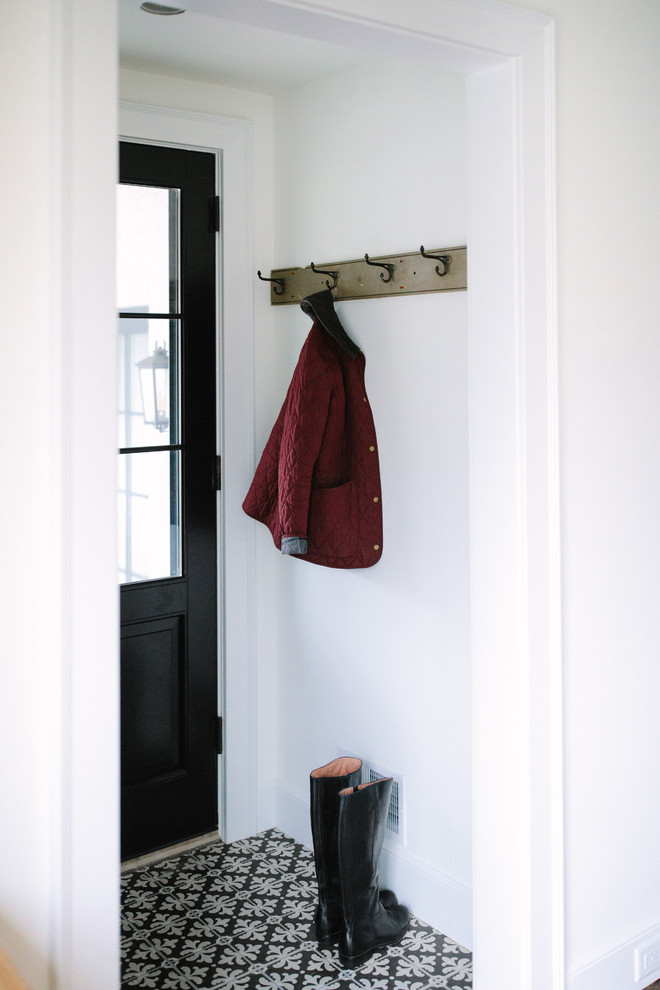 Foto på en liten vintage foajé, med vita väggar, klinkergolv i porslin, en enkeldörr och en svart dörr