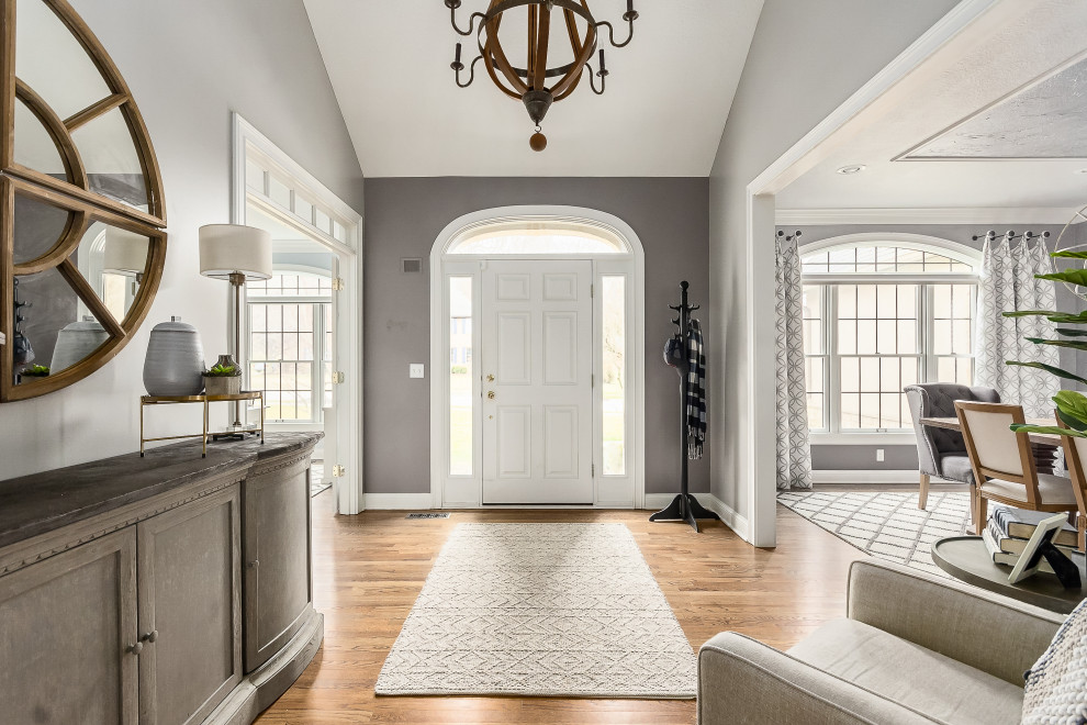 На фото: фойе в классическом стиле с серыми стенами, паркетным полом среднего тона, одностворчатой входной дверью, белой входной дверью, коричневым полом и сводчатым потолком с