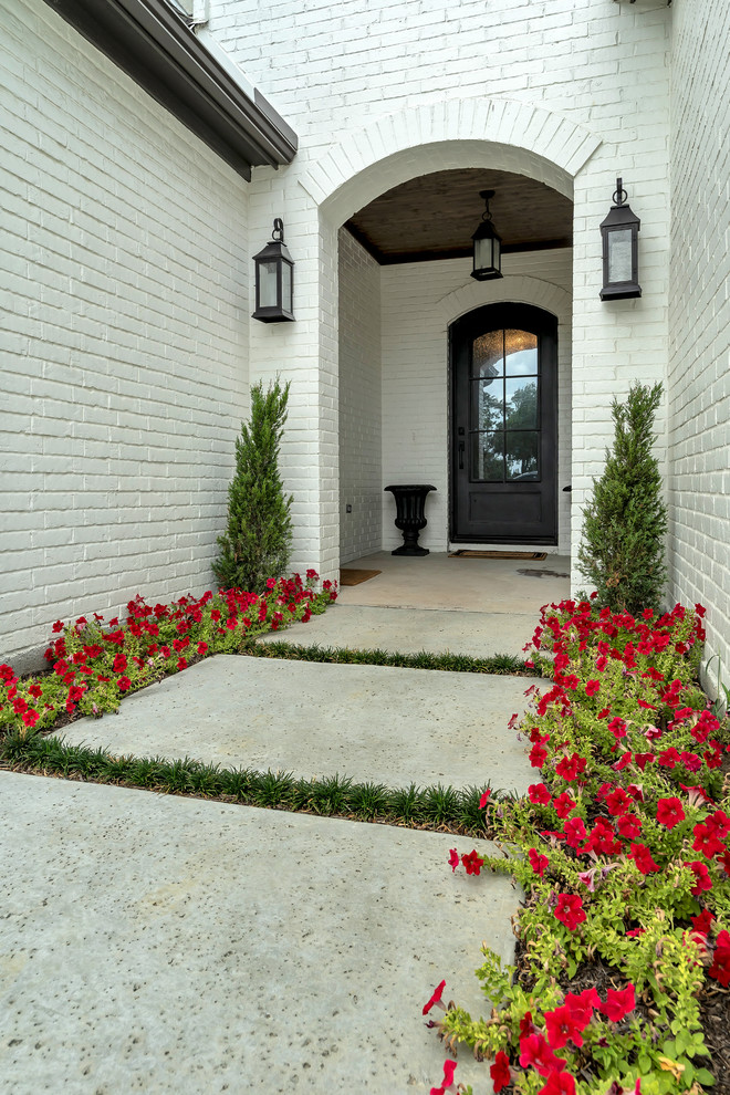 Modelo de entrada clásica renovada con paredes blancas, suelo de cemento, puerta simple, puerta metalizada y suelo beige