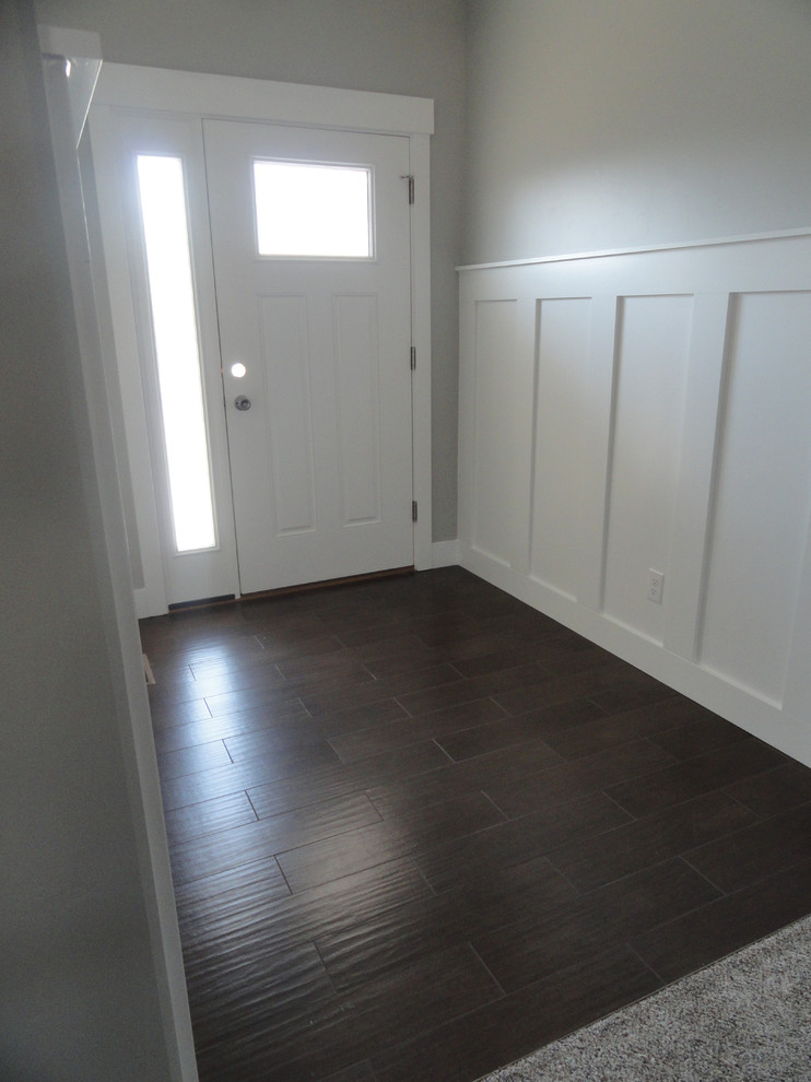 Idées déco pour une entrée craftsman de taille moyenne avec un couloir, un mur gris, parquet foncé, une porte simple et une porte blanche.