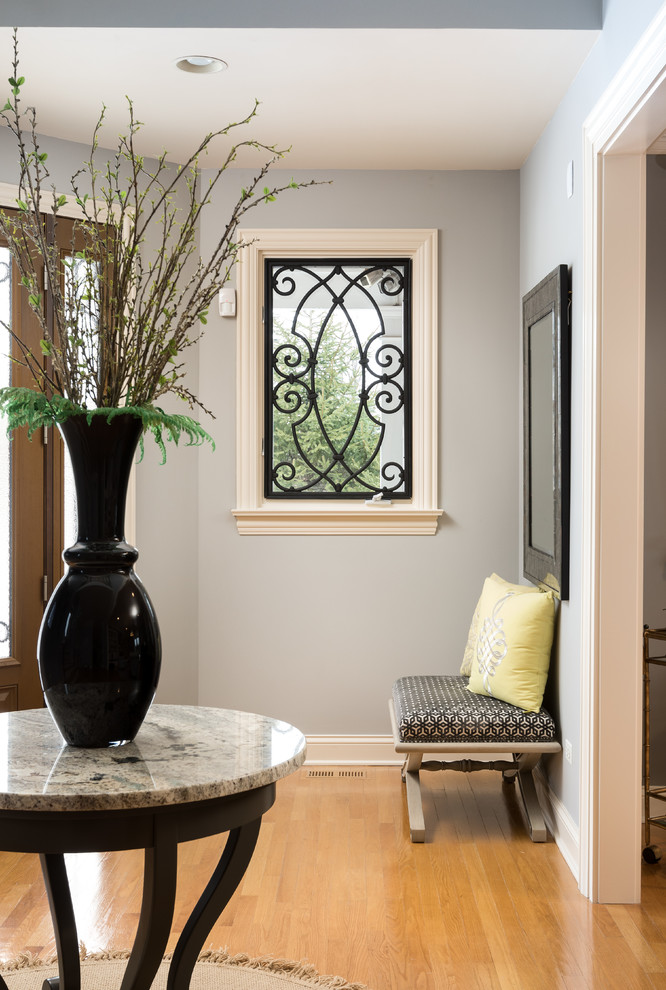 Imagen de distribuidor tradicional renovado de tamaño medio con paredes grises, suelo de madera clara, puerta simple, puerta de vidrio y suelo beige