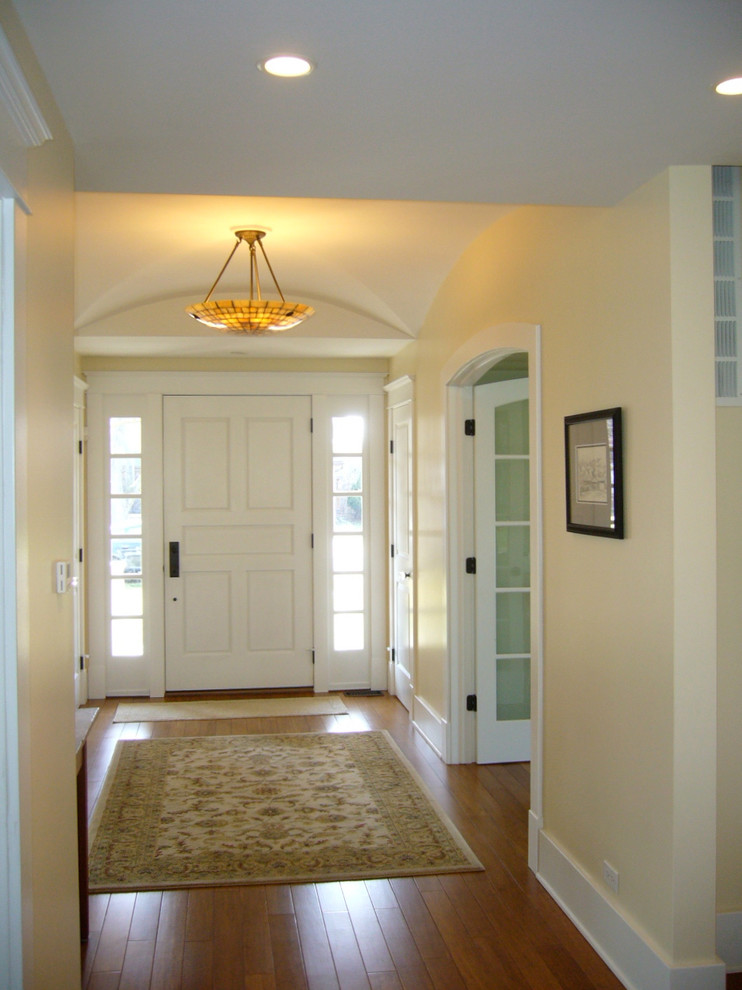 Foto de puerta principal clásica con paredes beige, suelo de madera en tonos medios, puerta simple y puerta blanca