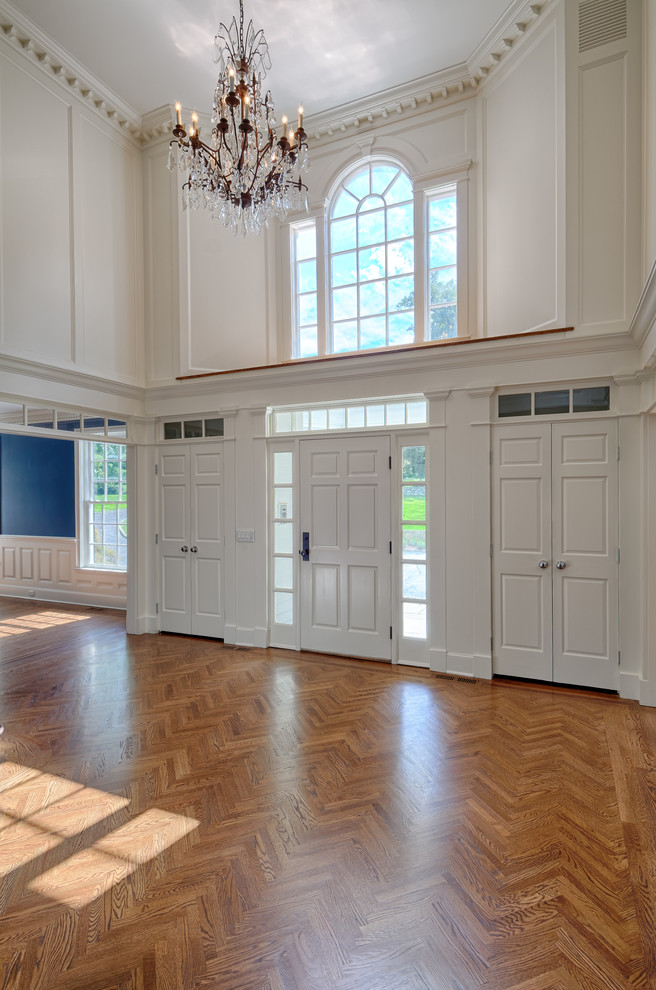 Großes Klassisches Foyer mit weißer Wandfarbe, Einzeltür, weißer Haustür und braunem Holzboden in New York