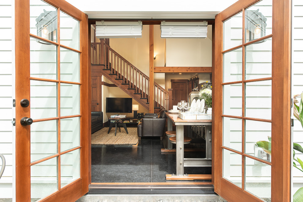 This is an example of a traditional front door in Seattle with white walls, concrete flooring, a double front door, a light wood front door and black floors.