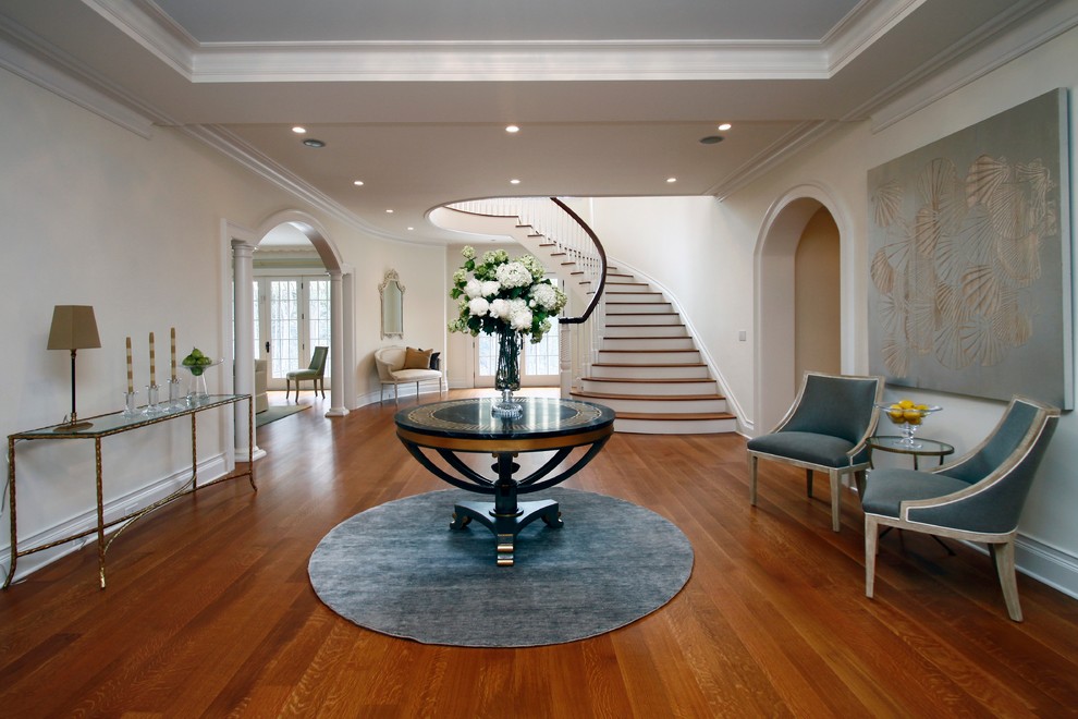 Photo of a classic foyer in New York with white walls, medium hardwood flooring and feature lighting.