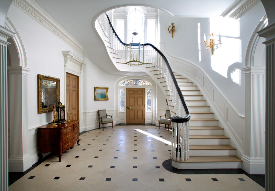 Geräumiges Klassisches Foyer mit weißer Wandfarbe, Kalkstein, Einzeltür, hellbrauner Holzhaustür und braunem Boden in New York