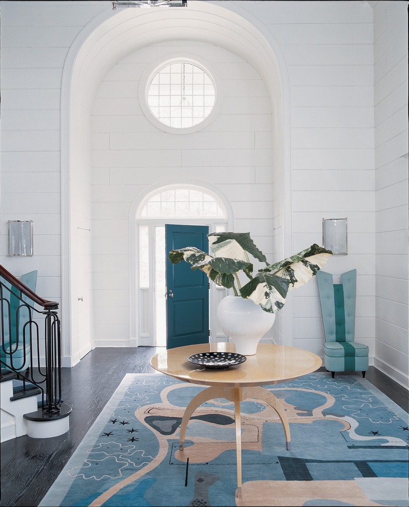 Réalisation d'un hall d'entrée tradition avec un mur blanc, parquet foncé, une porte simple et une porte bleue.