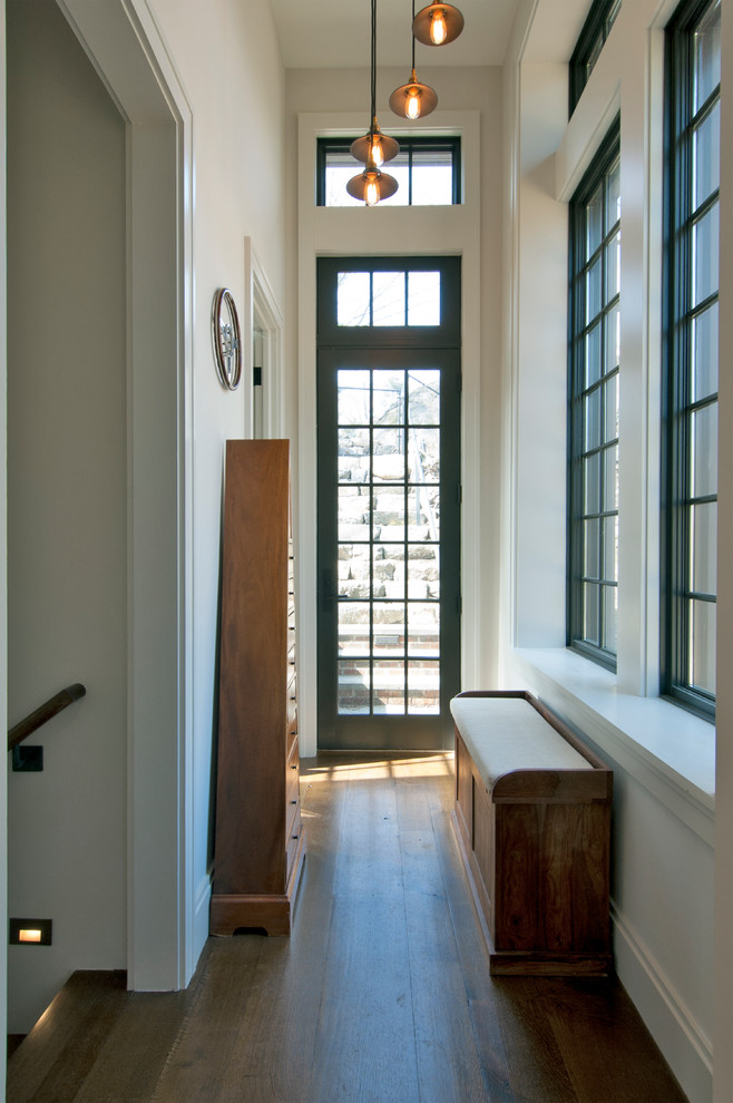 Immagine di un ingresso industriale di medie dimensioni con pareti bianche, pavimento in legno massello medio, una porta singola, una porta nera e pavimento marrone