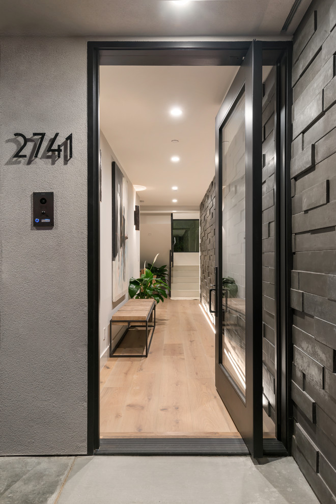 Idee per un corridoio design di medie dimensioni con parquet chiaro, una porta singola, una porta in vetro, pavimento marrone e pareti grigie