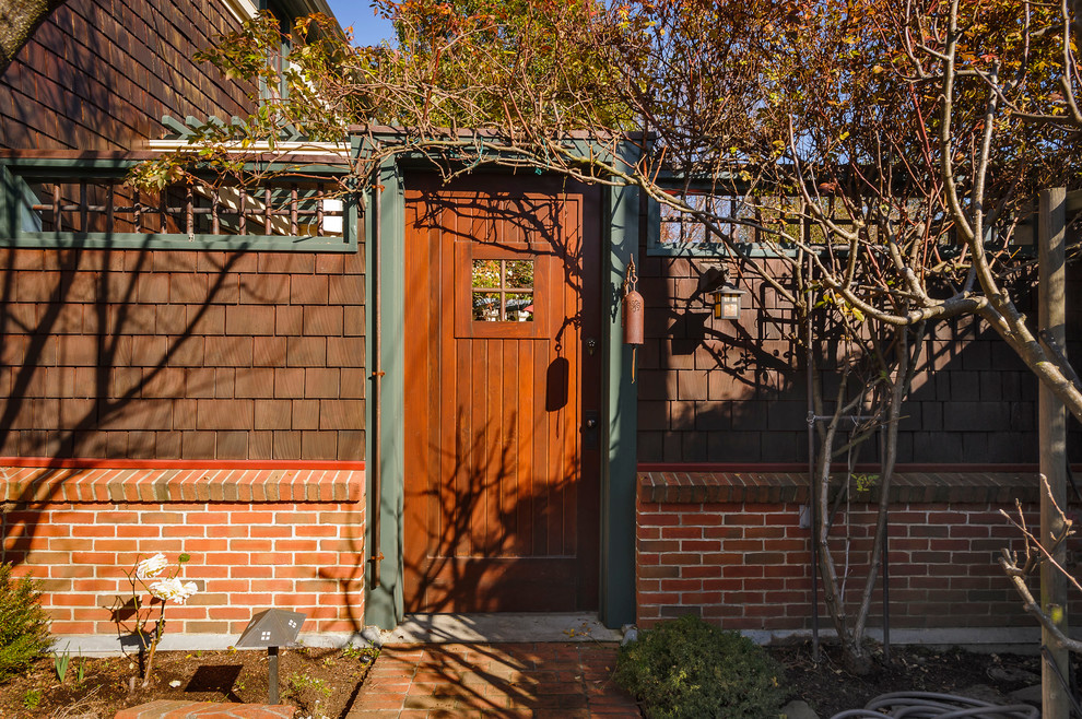 Ejemplo de entrada de estilo americano con puerta simple y puerta de madera en tonos medios