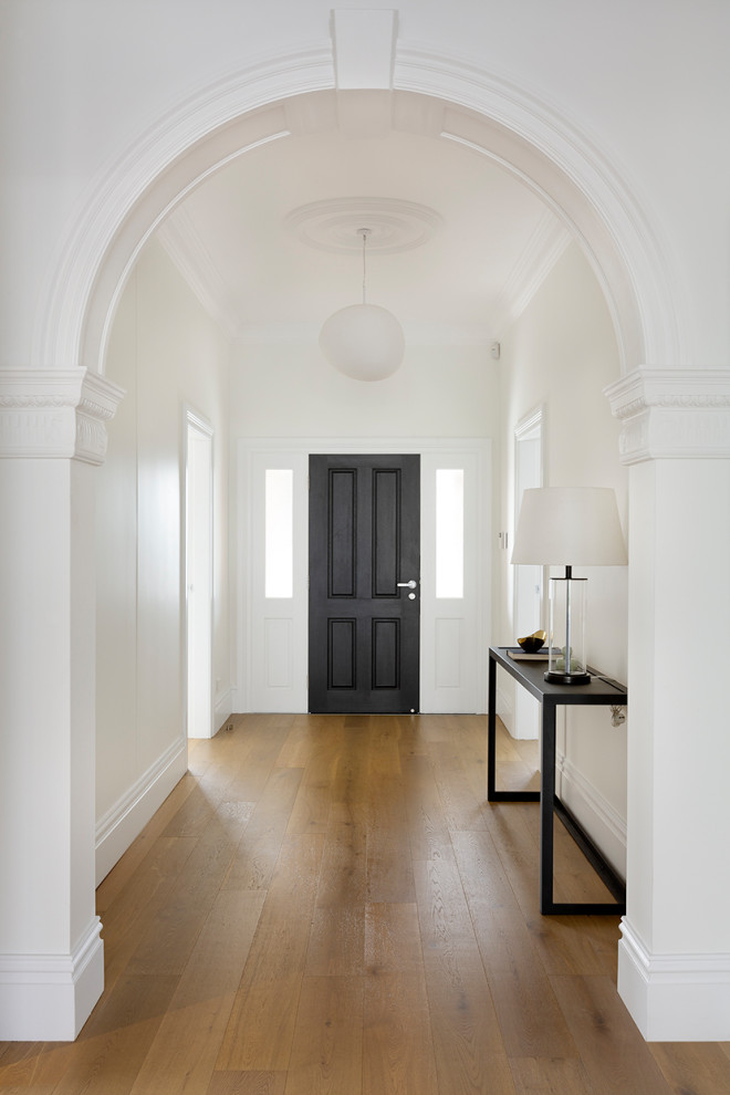 シドニーにある高級な広いヴィクトリアン調のおしゃれな玄関ホール (白い壁、無垢フローリング、黒いドア、茶色い床) の写真