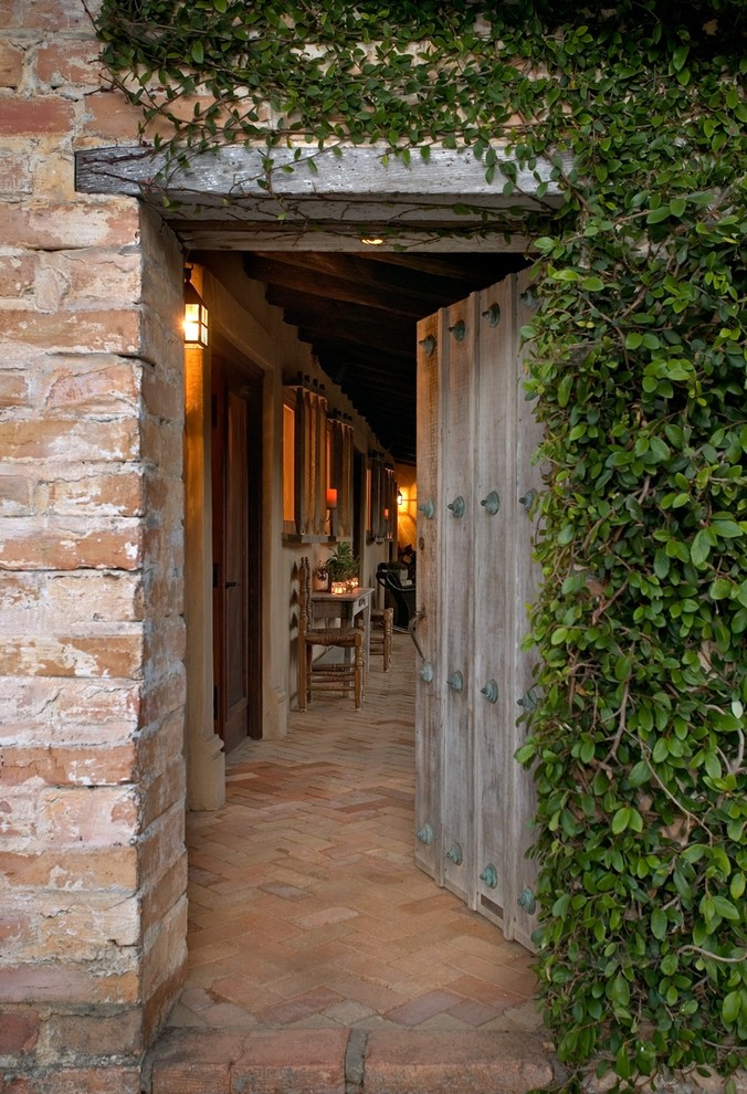 Foto de entrada campestre con suelo de ladrillo y puerta simple