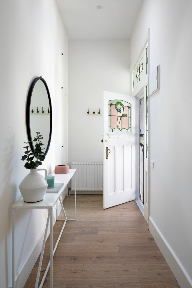 メルボルンにある高級な中くらいなモダンスタイルのおしゃれな玄関ドア (白い壁、淡色無垢フローリング、白いドア、茶色い床) の写真