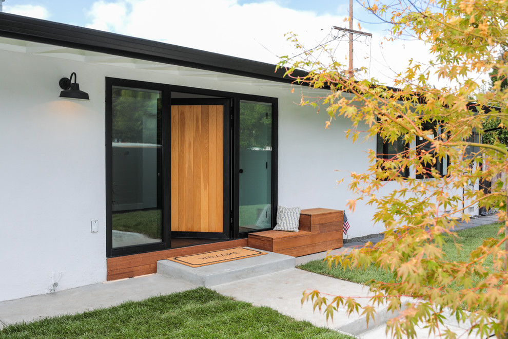 На фото: входная дверь среднего размера в стиле модернизм с белыми стенами, темным паркетным полом, поворотной входной дверью, входной дверью из светлого дерева и коричневым полом