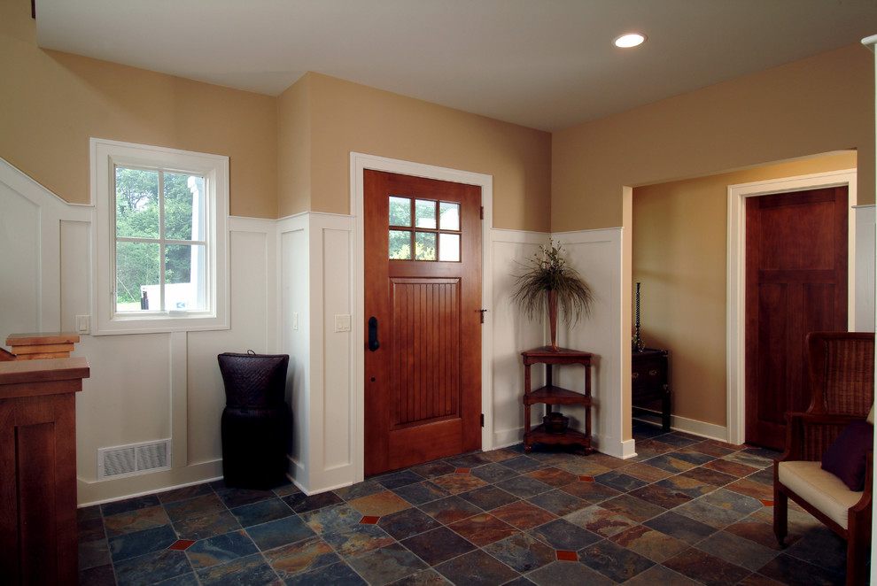 Imagen de puerta principal tradicional de tamaño medio con paredes beige, suelo de pizarra y puerta de madera oscura