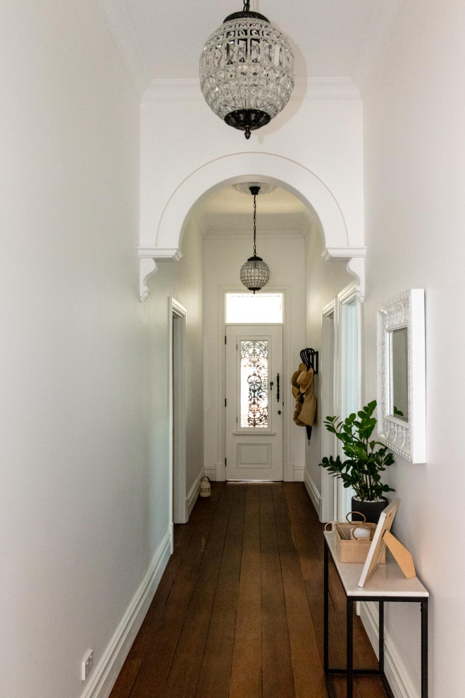 Ispirazione per un corridoio tradizionale con pareti bianche, pavimento in legno massello medio, una porta singola e una porta bianca