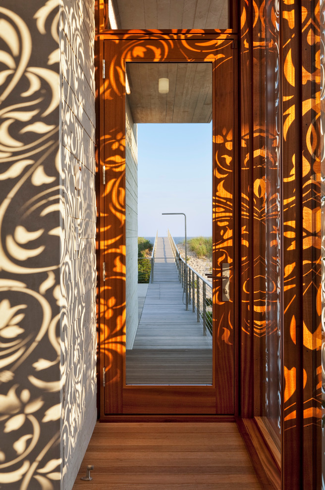 Idée de décoration pour une porte d'entrée marine avec une porte simple, une porte en verre, un mur marron, un sol en bois brun et un sol marron.