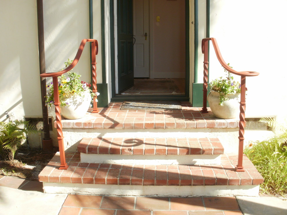 Modelo de puerta principal mediterránea de tamaño medio con paredes rosas, puerta simple y puerta verde