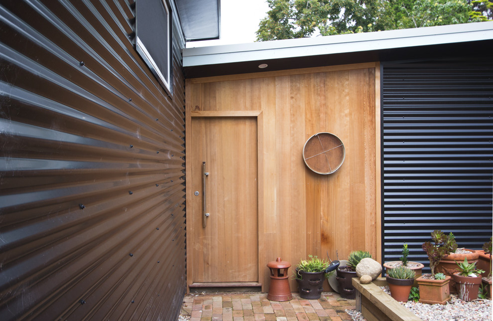 Foto de puerta principal industrial con puerta simple, puerta de madera clara y paredes negras