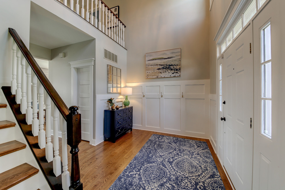 ダラスにある広いトランジショナルスタイルのおしゃれな玄関ロビー (グレーの壁、淡色無垢フローリング、白いドア、茶色い床) の写真