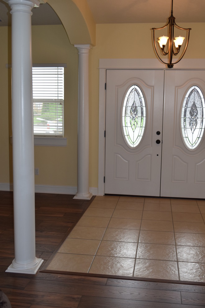 Foto de puerta principal clásica grande con paredes amarillas, suelo de madera en tonos medios, puerta doble y puerta blanca