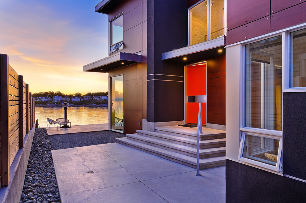 Contemporary entrance in Vancouver with a single front door, an orange front door and feature lighting.