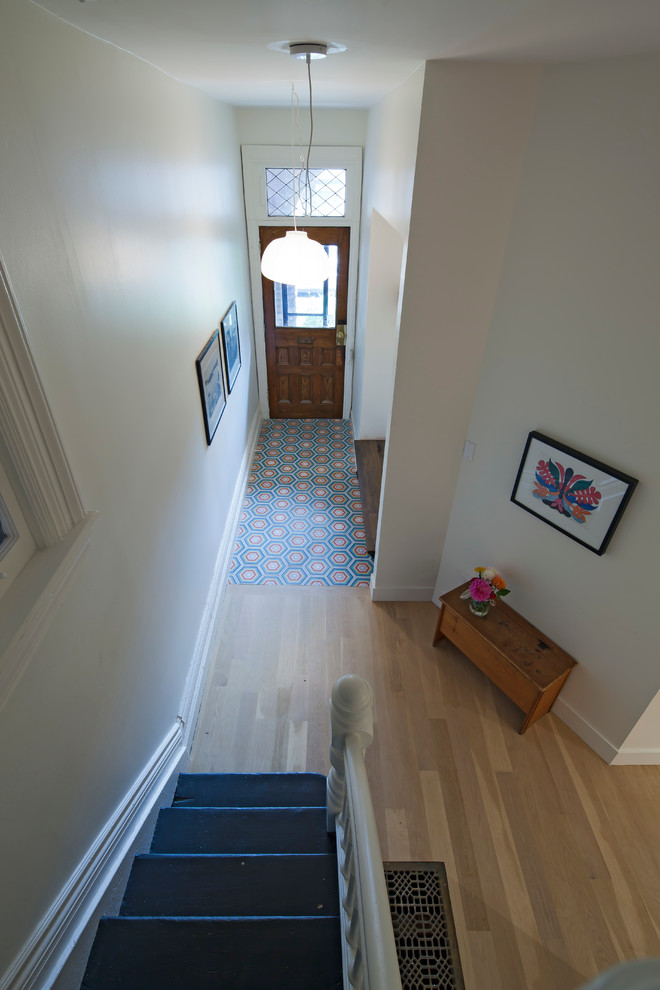 トロントにあるお手頃価格の中くらいなヴィクトリアン調のおしゃれな玄関ロビー (白い壁、セラミックタイルの床、木目調のドア) の写真
