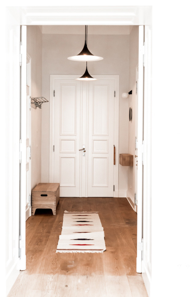 Esempio di una porta d'ingresso minimalista di medie dimensioni con pareti grigie, parquet chiaro, una porta a due ante e una porta bianca