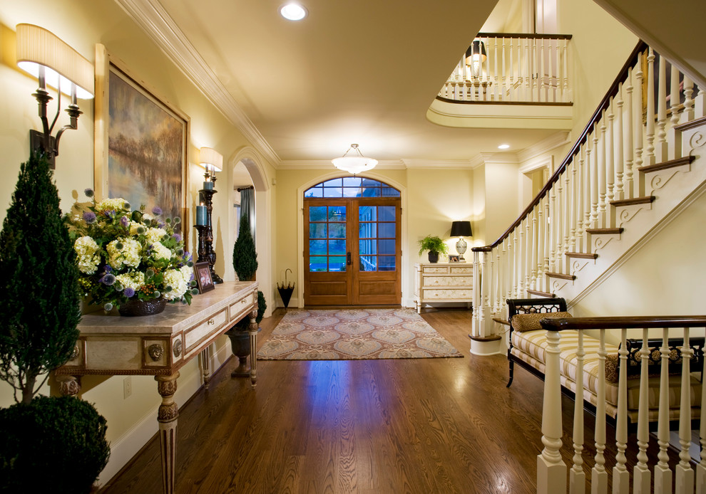 Elegant medium tone wood floor entryway photo in Philadelphia with beige walls and a glass front door